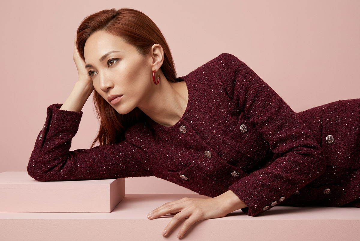 Foto da catalogo alta moda con modella ramata, abito bordeaux e sfondo rosa